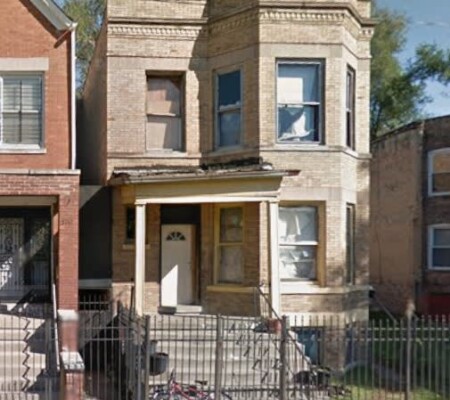 5749 S. Laflin Street, c.1900, Back of the Yards. A two-story buff brick two-flat with a projecting three-sided bay, corbelled brick cornice and a wood entry porch. City-owned. Emergency demolition, August 2026. Photo credit: Google Maps