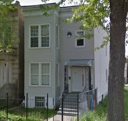 4019 W. Monroe Street, c.1900, West Garfield Park. A two-story frame two-flat with clapboard siding, a full-height projecting bay, an octagonal attic window and a metal entry canopy. Demolished August 2026. Photo credit: Google Maps