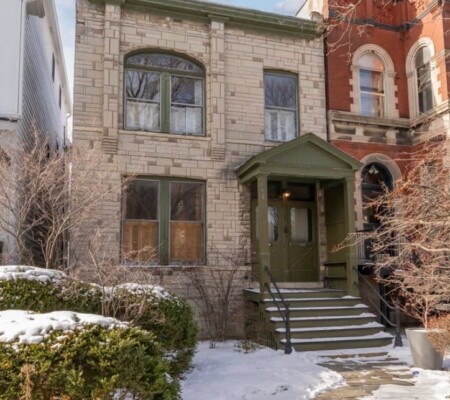 2438 N. Burling Street, c.1890, Lincoln Park. A two-story rock-faced limestone residence with an arched art glass window, stone stoop and projecting wood entry portico. Demolished August 2026. Photo credit: Redfin