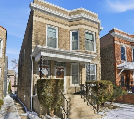 1736 W. Farragut Avenue, c.1910, Andersonville. A buff brick two-flat with a projecting three-sided bay, bracketed metal cornice and a full-width porch with ornamental ironwork. Demolished August 2026. Photo credit: Redfin